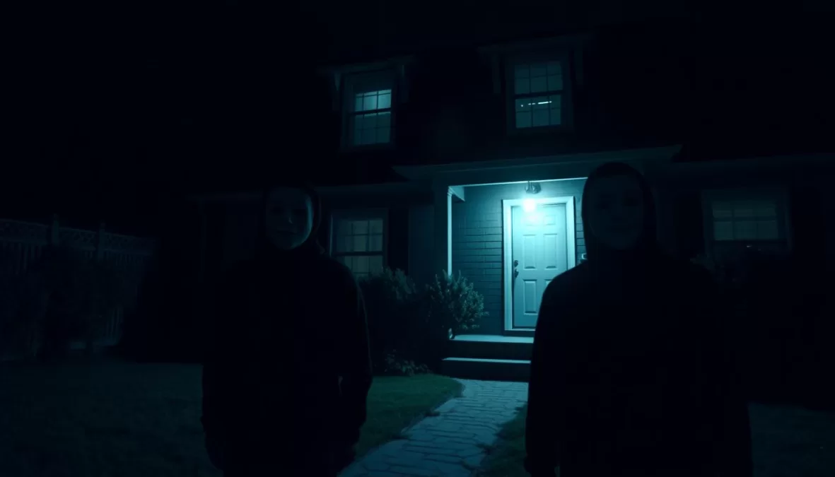 A creepy scene from The Strangers showing masked intruders watching a house at night, an honorable mention among scariest movies on Netflix 2025