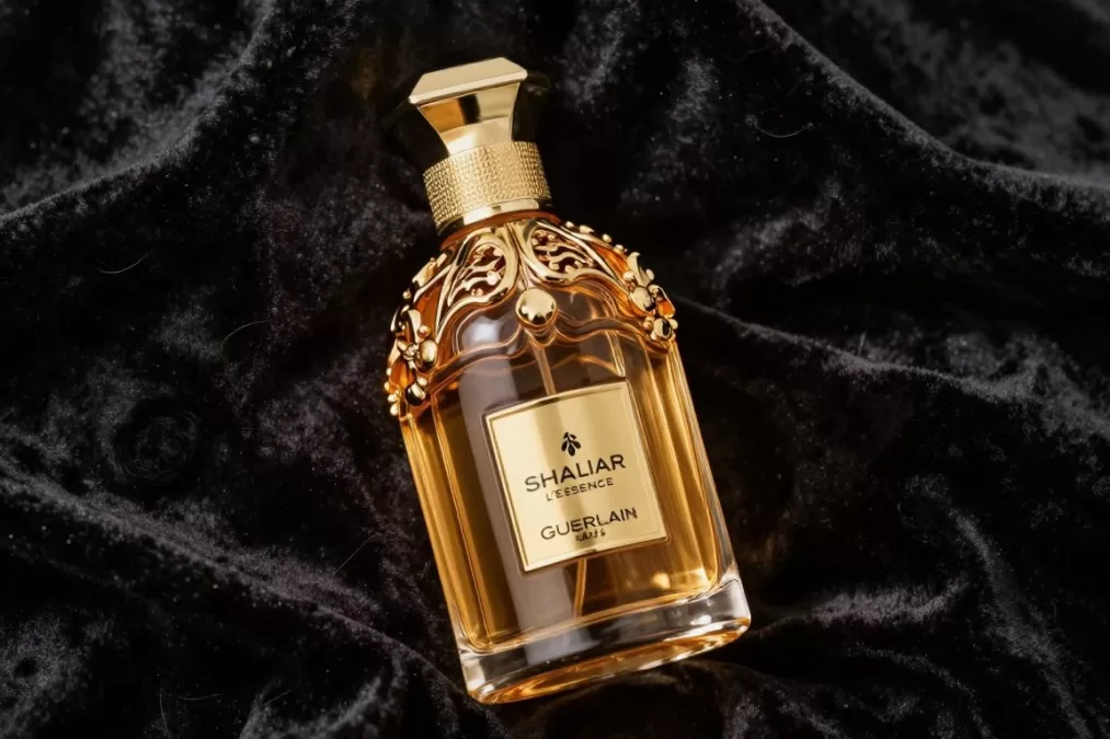 Guerlain Shalimar L'Essence bottle with ornate design against winter backdrop