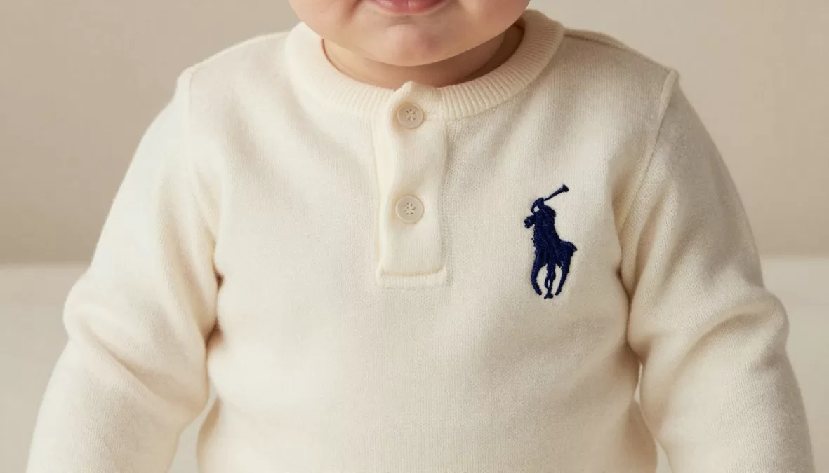 Baby dressed in Ralph Lauren cashmere outfit with signature embroidered polo player logo, representing Most Expensive Baby Clothing Brands