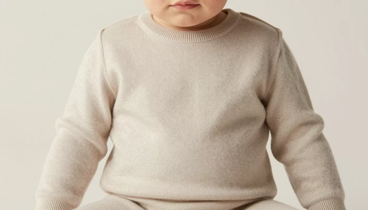 Baby wearing Loro Piana cashmere outfit in neutral tones with minimalist design, showcasing one of the Most Expensive Baby Clothing Brands