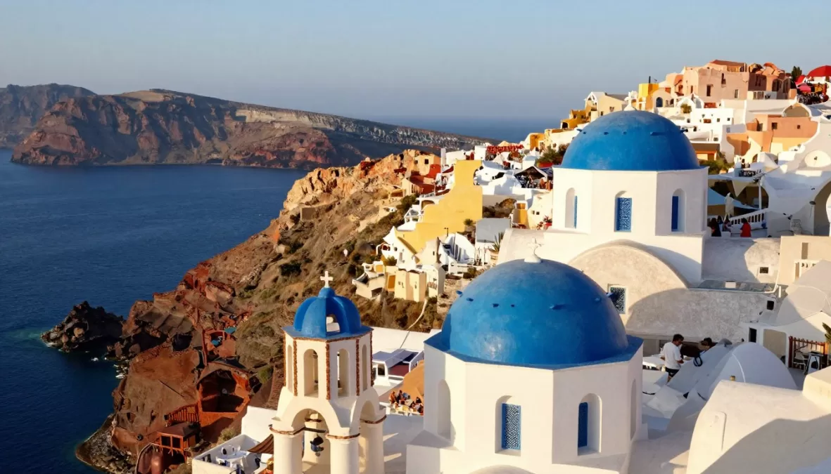 Santorini's white buildings and blue domes with sunset views in summer 2026