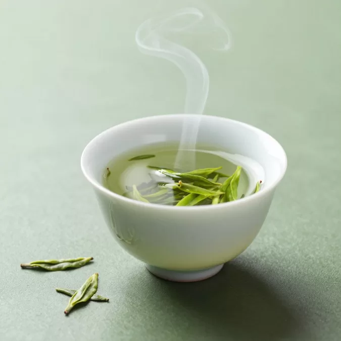 green tea in traditional cup with tea leaves showing L-theanine and antioxidant benefits