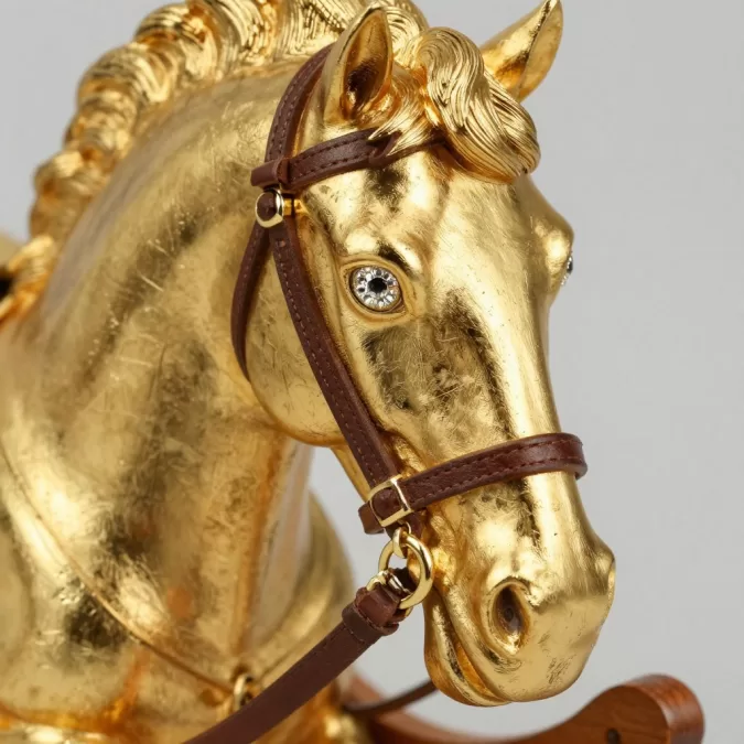 Close-up of gold rocking horse showing intricate carving details and gold leaf application