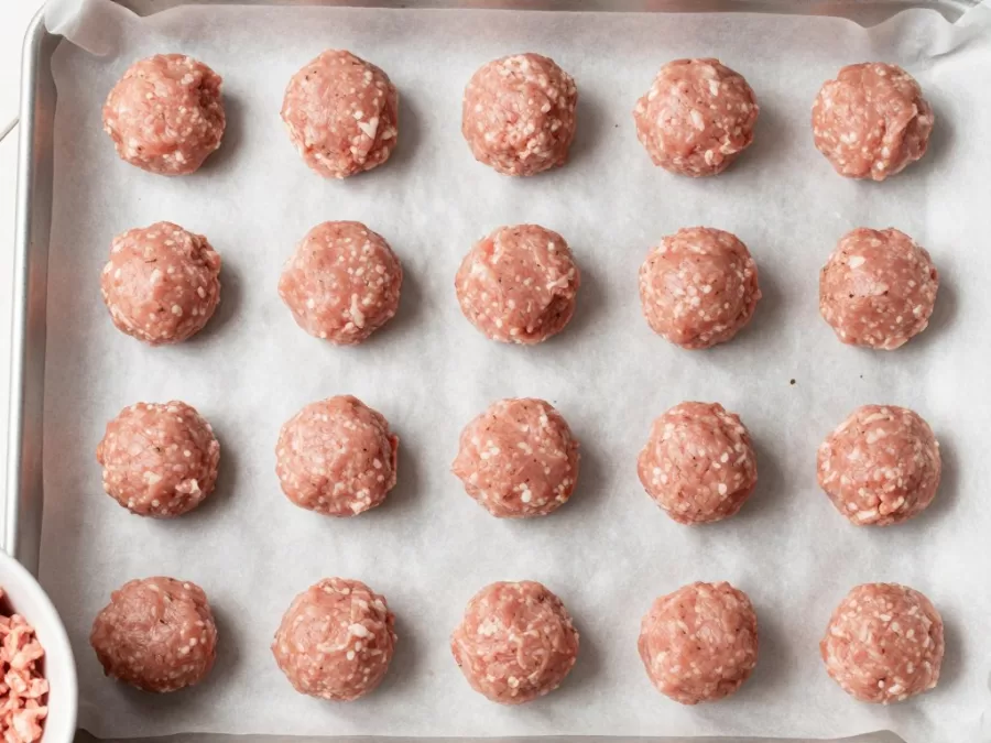 Raw chicken meatballs on baking sheet before cooking
