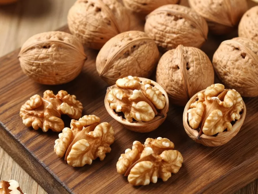 Walnuts whole and shelled displayed on a wooden cutting board