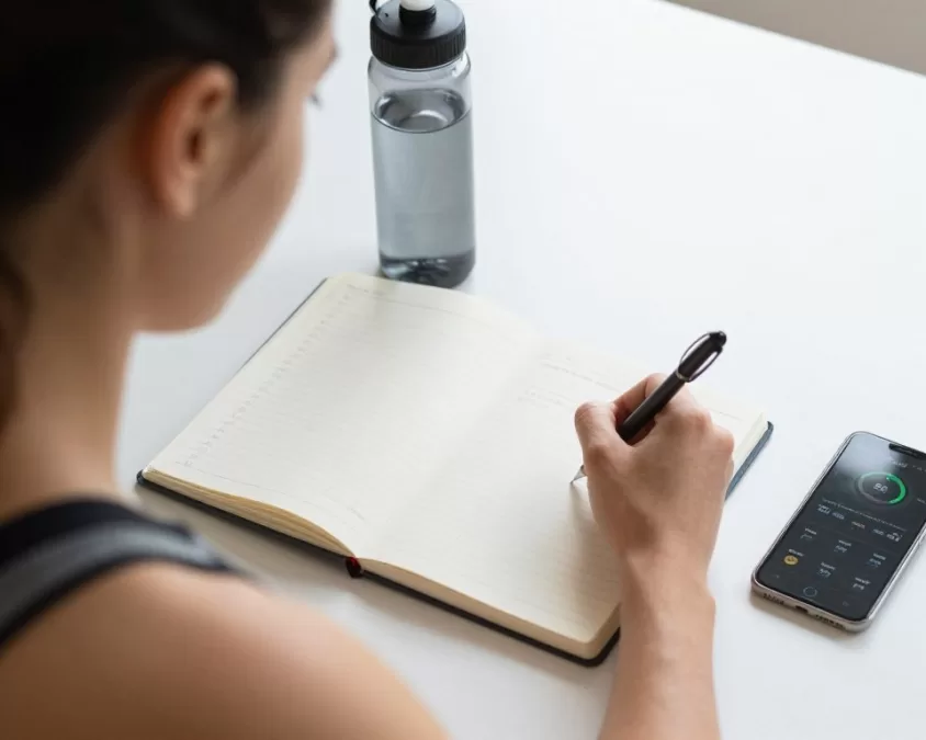 Beginner tracking workout progress in fitness journal with gradual improvements shown