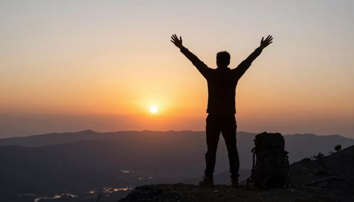 Solo traveler watching sunset over mountains, sense of accomplishment