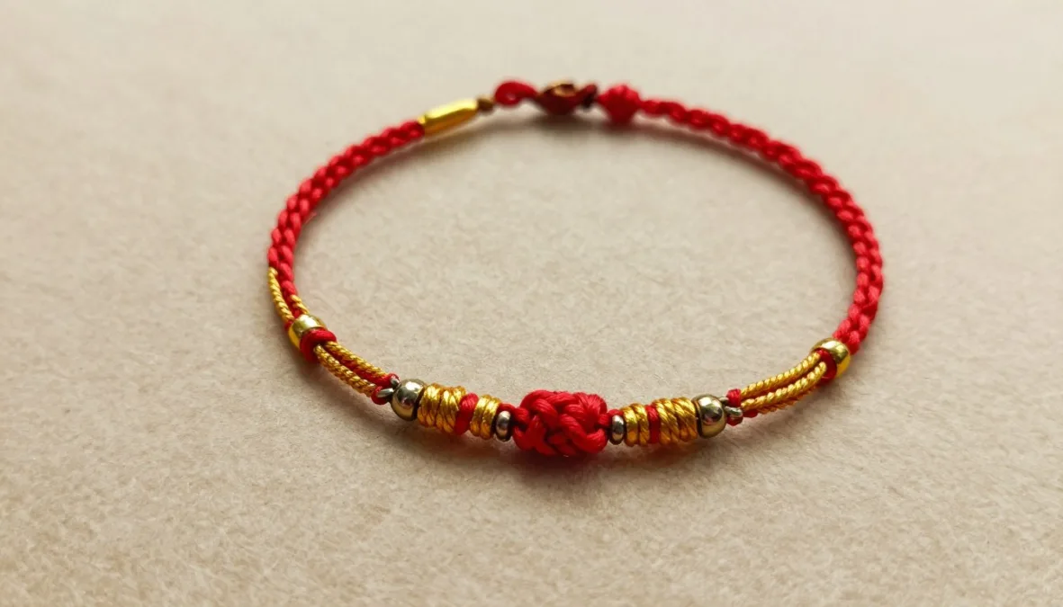 Traditional rakhi with red and gold threads in simple elegant design