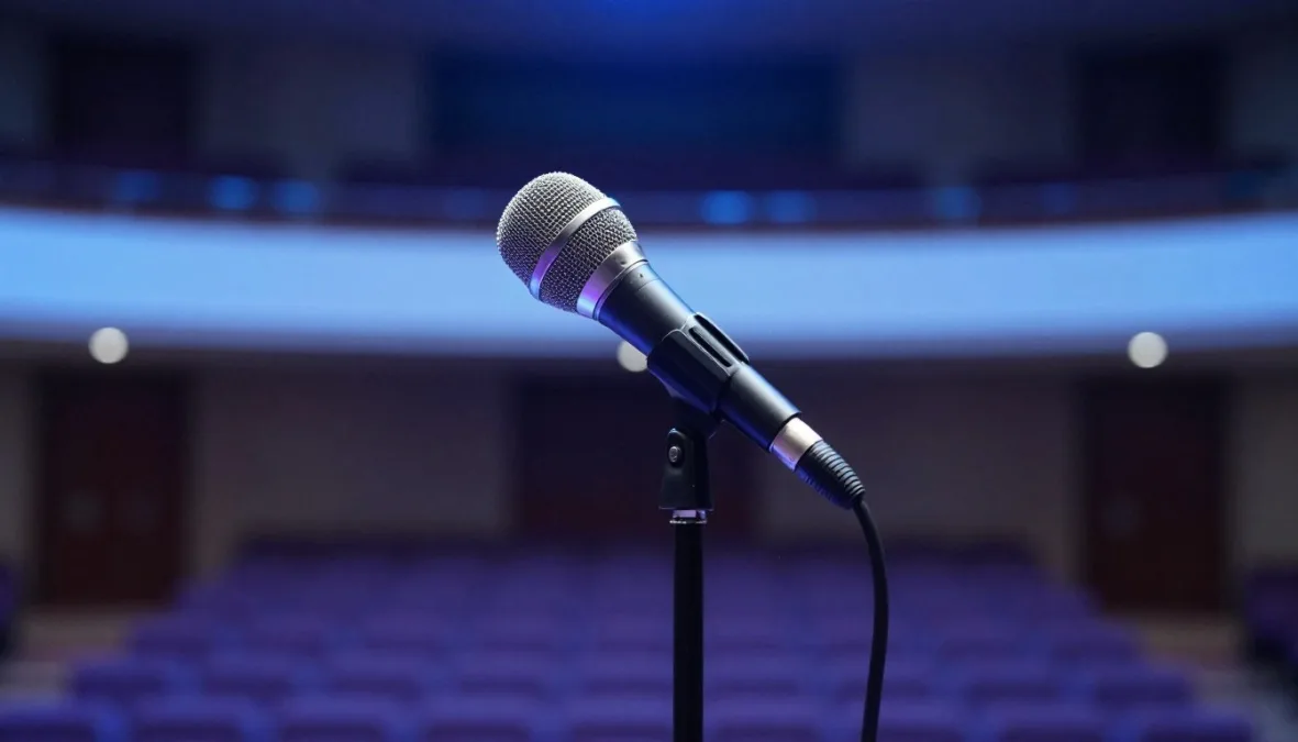 A classic chrome studio microphone illuminated by blue stage lights