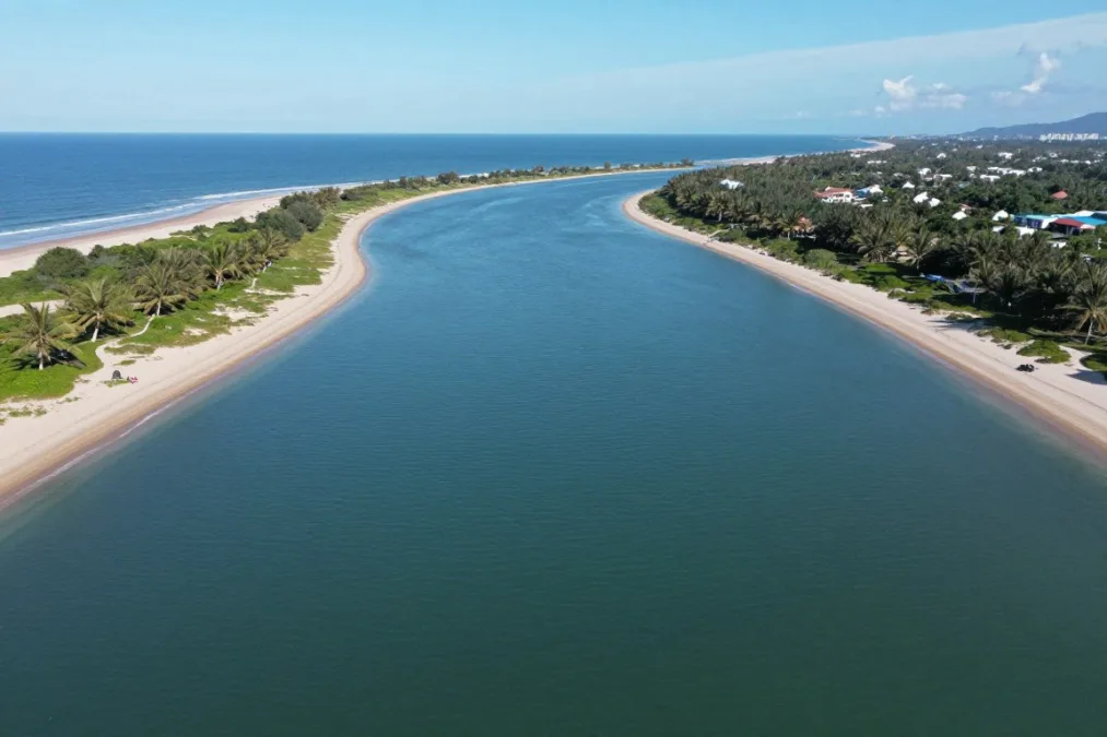 A coastal barrier island inlet surrounded by deep blue water under direct sunlight