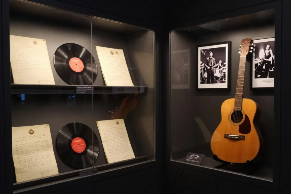 Carefully arranged museum display cases showing vintage letters, vinyl records, and performance memorabilia Carefully arranged museum display cases showing vintage letters, vinyl records, and performance memorabilia
