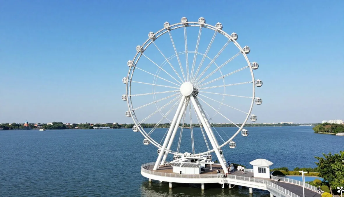 Large observation Ferris wheel on a pier reaching into an expansive blue lake Large observation Ferris wheel on a pier reaching into an expansive blue lake