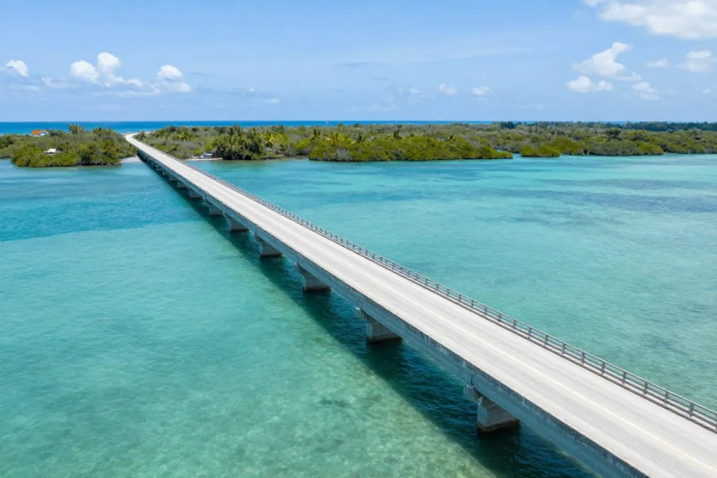 Ocean highway bridge crossing clear coastal waters under scattered clouds